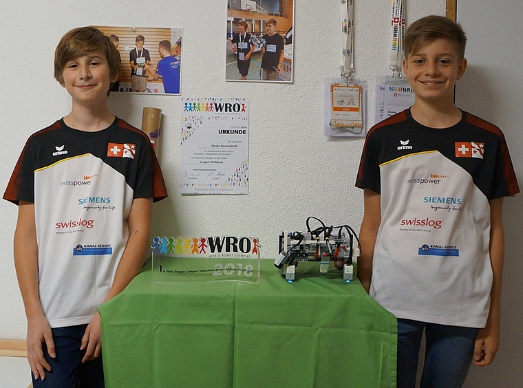 Jakob Hechler (l.) und Nicola Alessandrelli mit ihrem eigens gebauten und programmierten Roboter und dem Gewinner-Pokal der Vorausscheidung, mit dem sie sich für die World Robot Olympiad in Thailand qualifizierten. (Bild: Franz Beidler)