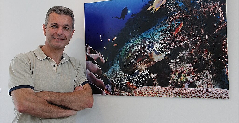 Der Unterwasserfotograf Piero Ambrosone neben seiner eindrücklichen Aufnahme einer Meeresschildkröte. (Bild: mim)