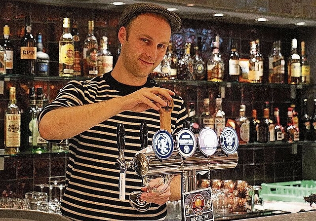 Der politisch aktive Luc Nünlist am Zapfhahn des Restaurants Pure, das er seit Kurzem mit seinem Dreitannenbier beliefern darf. (Bild: Denise Donatsch)