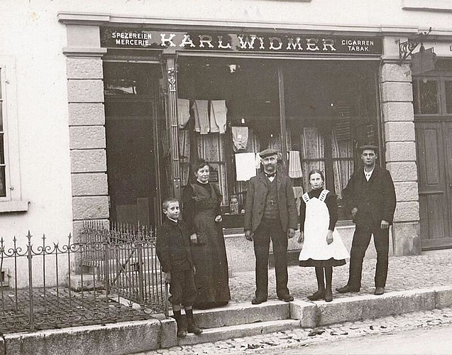 Marie und Karl Widmer-Weisskopf mit ihren Kindern Karl und Julie sowie einem Angestellten vor ihrem Lädeli (um 1910).
