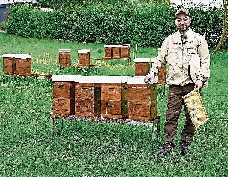 Maschinenbautechniker und Imker Pascal Müller hat vor, die Imkerei zu vergrössern, sodass noch mehr lokaler Honig angeboten werden kann. Hier steht er inmitten der Bienenkästen, die von seinem Vater gezimmert werden. (Bild: Denise Donatsch)