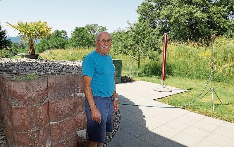 Markus Graber steht im Sommer 2022 trockenen Fusses und durch den Damm im Hintergrund bestens geschützt auf seinem Gartensitzplatz. (Bild: Achim Günter)
