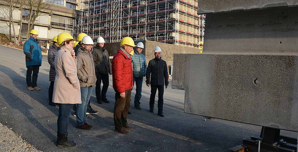 Peter Trost (M.), Architekt der Batimo AG Architekten SIA, erklärt der Besuchergruppe, wie die Sanierung der Betonelemente bewerkstelligt wird. (Bild: vwe)